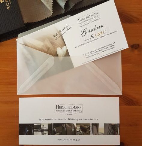Gutschein für Maßanzug und Maßkonfektion von Herschelmann, maßgeschneiderter Anzug aus Stoffen von Scabal. Geschenkgutschein mit Stoffbündel.